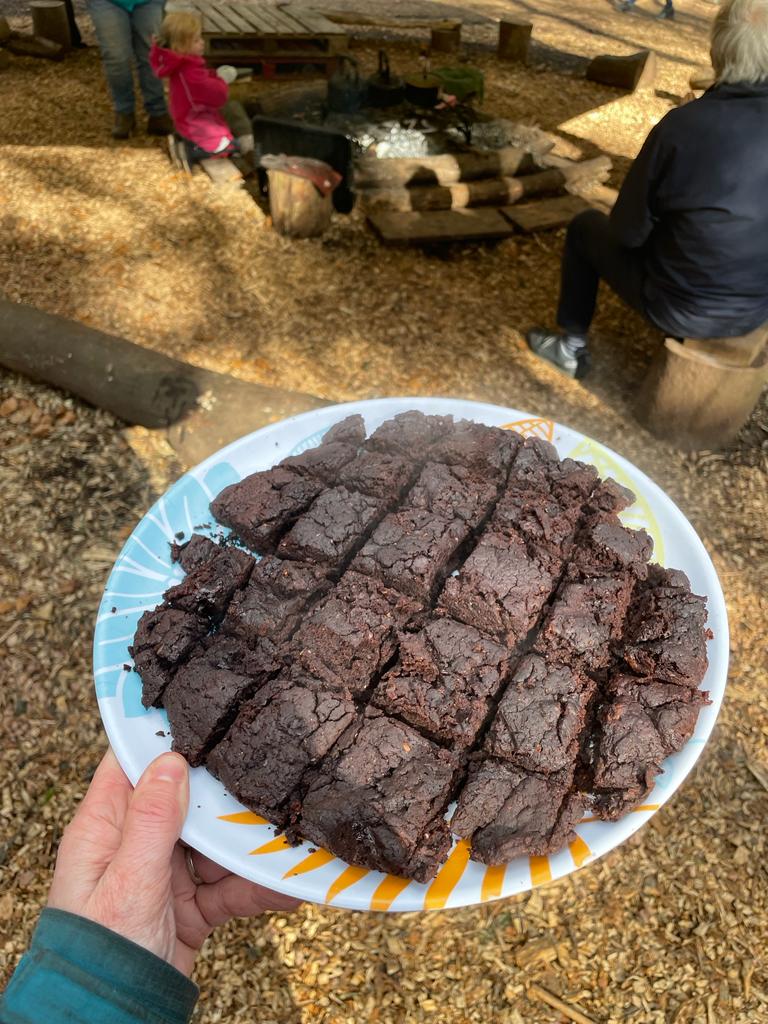 someone holding a plate full of vegan chocolate brownies. 